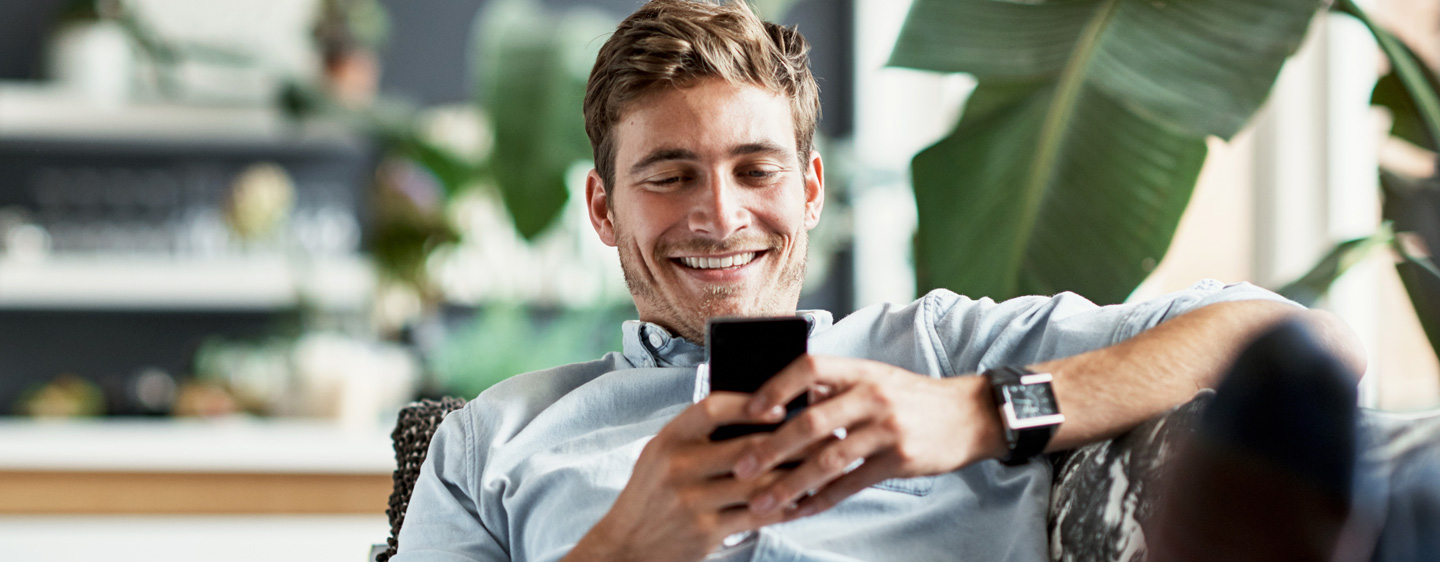 A man smiles as he uses his cellphone.