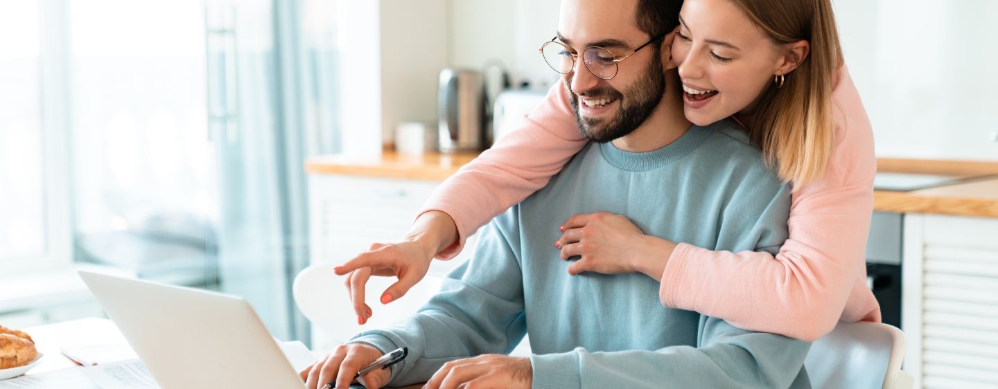 Couple looking excitedly at computer. 