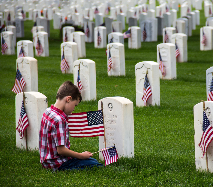 Image of young boy at the grave of a fallen soldier
