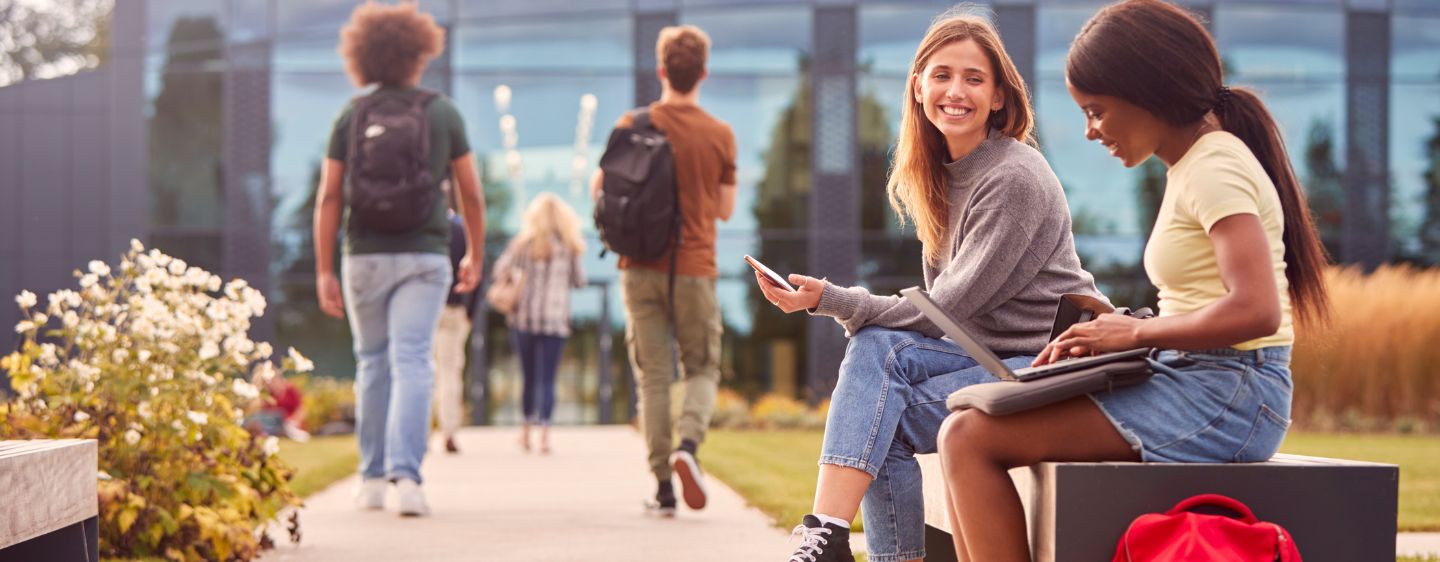 Two students sitting on university bench. 