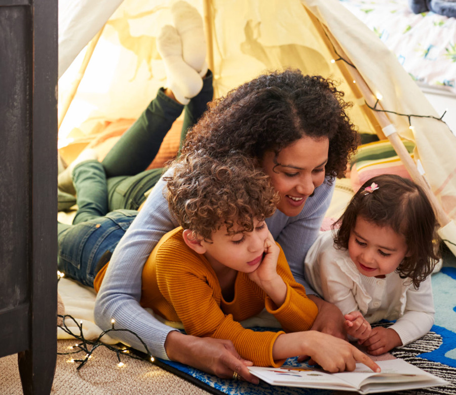 Image of a mom reading on the floor with her two kids.