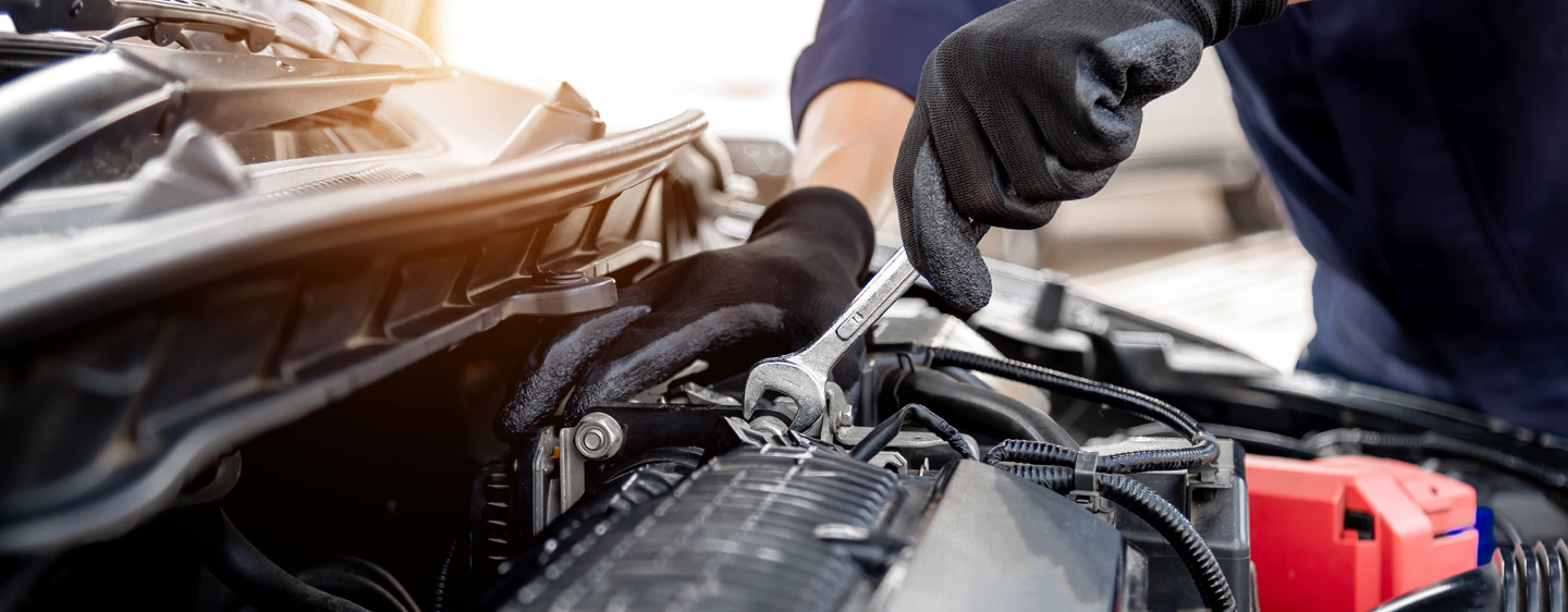 Image of a mechanic working under a car's hood.