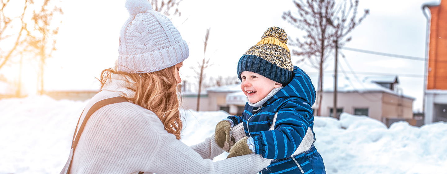 Mother plays with young son in the snow