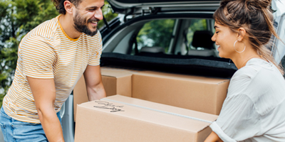 Image of a man and woman carrying a box together that says Shred Day on top of it.