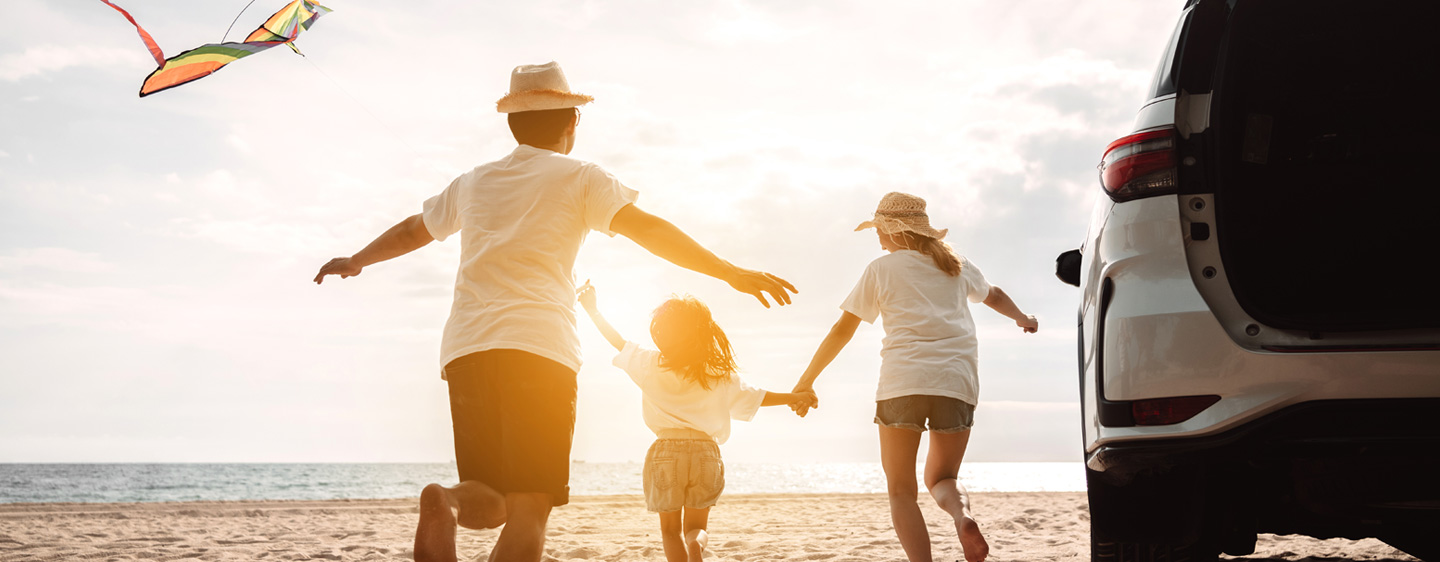 Image of a man, woman, and child running to the ocean.