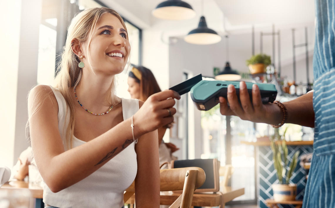 Image of a woman paying with her card at a restaurant. 