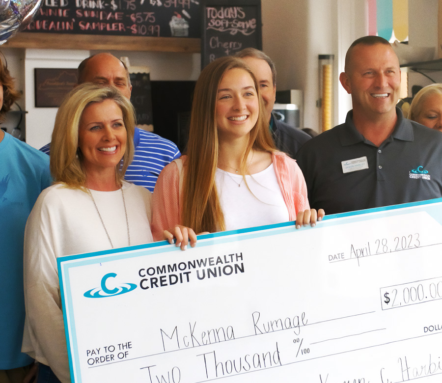 Image of a scholarship winner holding a large check and smiling with a CCU team member.