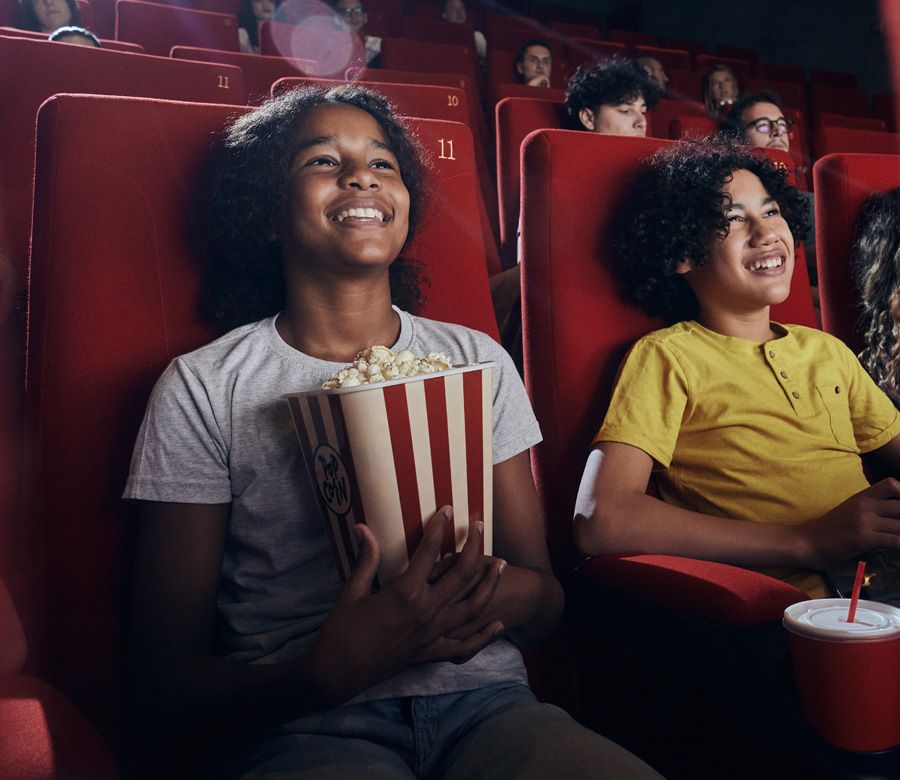Image of two teens watching a movie in a theater.