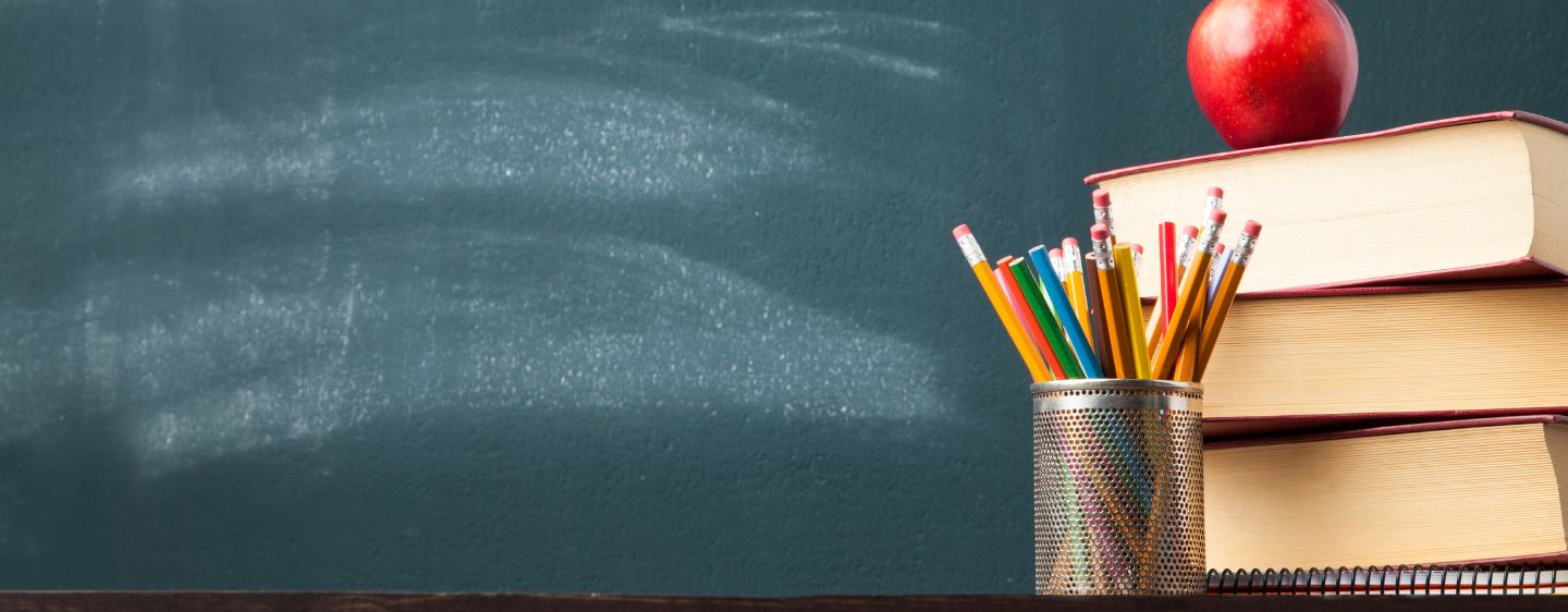 Photo of chalk board, pencils, books, and apple. 