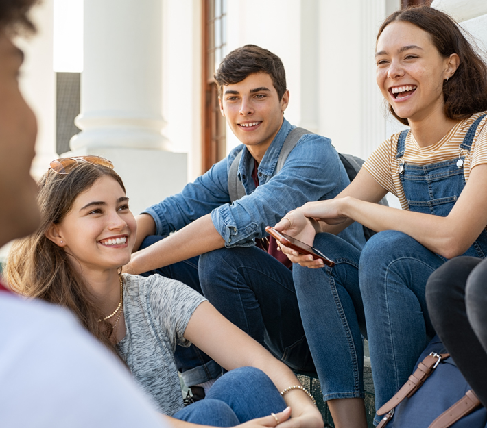 Teens sitting together having a conversation and smiling.
