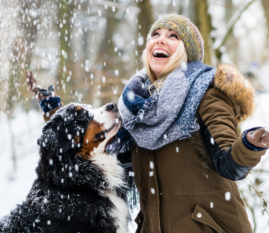 Woman playing with her dog in the snow